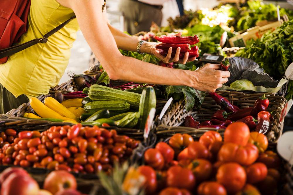 Femme choisissant des légumes sur un étal de légumes au marché